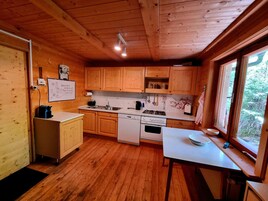 Cocina de cabaña de madera con estufa, pileta y alacenas de madera.