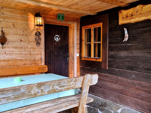 A wooden cabin with a dark door, a window with wooden shutters, and a bench outside. - Alpine Hut in Murau Near Ski Slope (Sankt Georgen am Kreischberg)