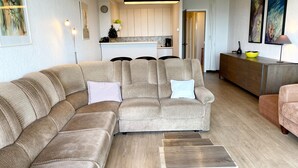 A modern living room with a sectional sofa, a small coffee table, and a kitchen in the background.