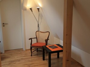 Cozy retreat with a single chair, wooden floor, and sloped ceiling.
