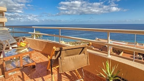 A balcony with a view of the ocean, a table with fruits, and a chair. - Apartment in Radazul With Stunning Sea Views (El Rosario)