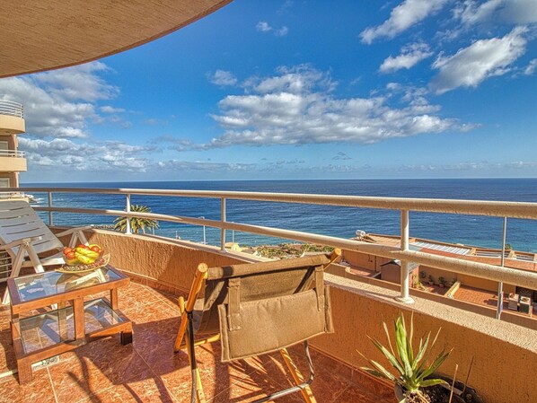 A balcony with a view of the ocean, a table with fruits, and a chair. - Apartment in Radazul With Stunning Sea Views (El Rosario)