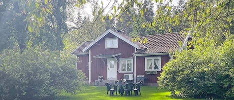Une maison rouge avec un porche à l’avant et une pelouse.