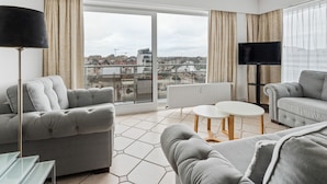 Een moderne woonkamer met grijze banken, een glazen salontafel en een tv op een dressoir.