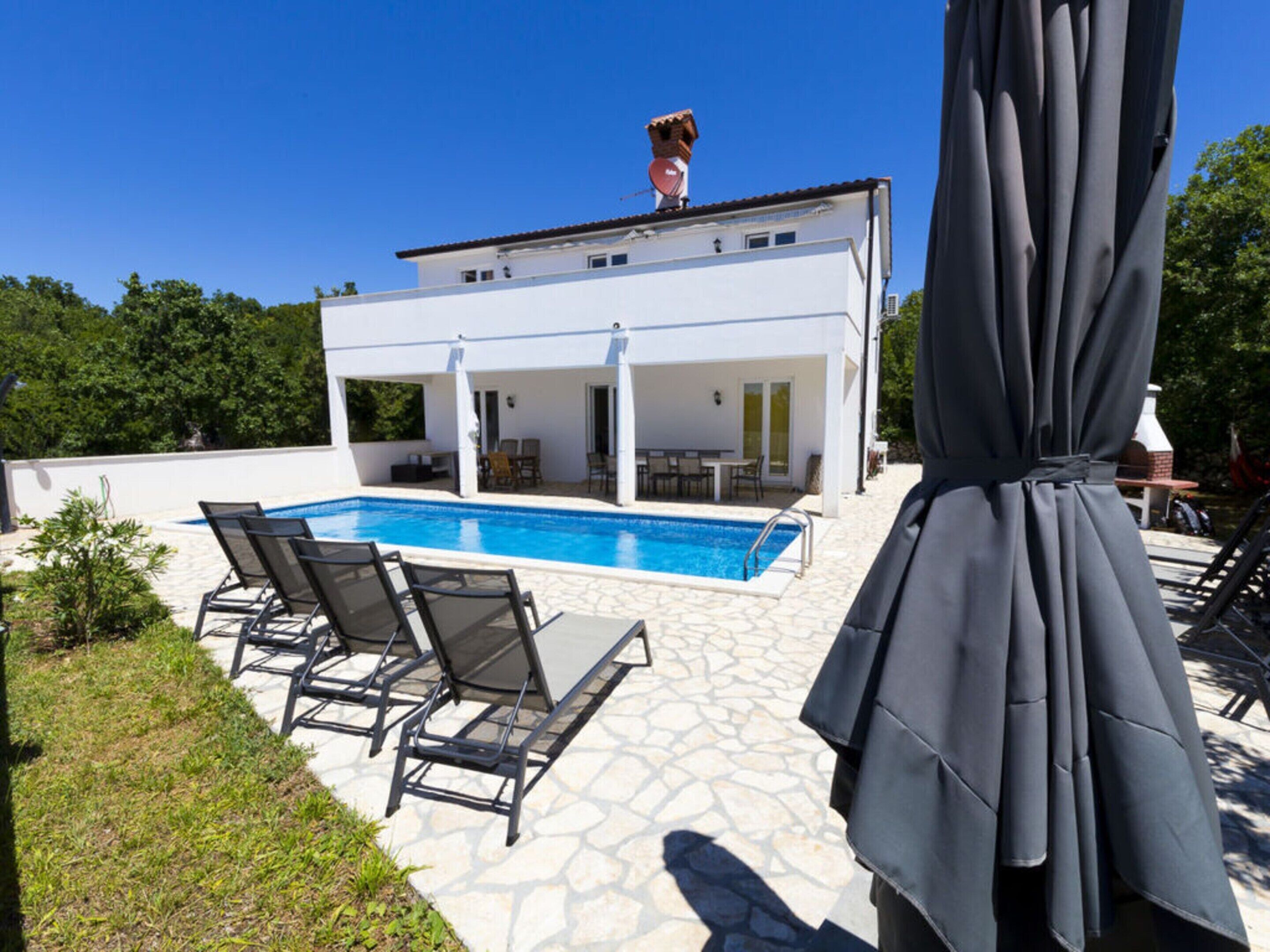 A modern house with a swimming pool, outdoor seating, and a covered patio area.