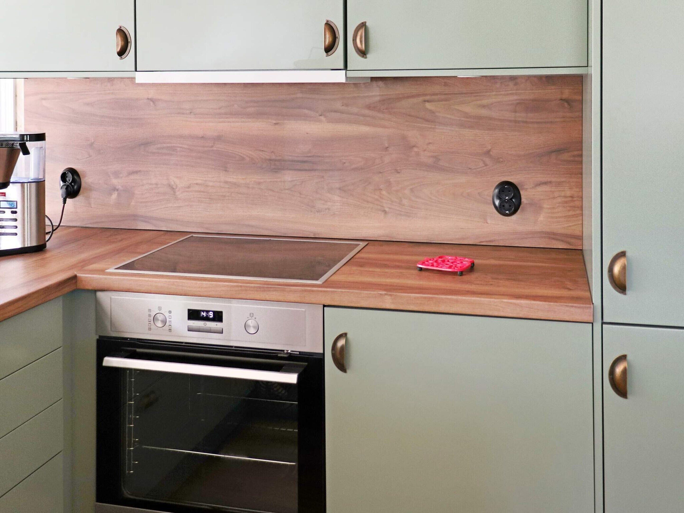 A kitchen with a built-in oven, a microwave, and a wooden countertop.