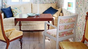 A cozy room with a sofa, two chairs, a wooden table, and floral wallpaper.