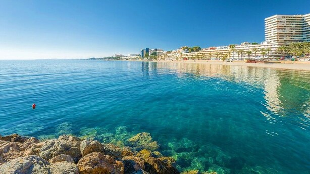 A coastal view with clear blue waters, a sandy beach, and a hotel with multiple floors and balconies overlooking the sea. - Mountain-view Apartment by Sea (Roquetas de Mar)