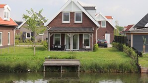 A residential house with a sloped roof, a front porch, and a car parked in the driveway.
