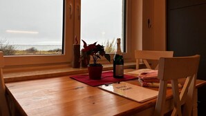 A wooden dining table with a red placemat, a bottle of champagne, and a potted plant. - Habel Modern Retreat (Nebel)