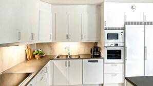 A modern kitchen with white cabinets, a stainless steel sink, a coffee maker, and a built-in oven. - 6 Person Holiday Home in Vikbolandet-by Traum (Vikbolandet)