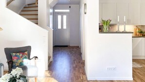 A modern interior with a staircase, a hallway leading to a door, and a kitchen area with white cabinets and a countertop. - 6 Person Holiday Home in Vikbolandet-by Traum (Vikbolandet)