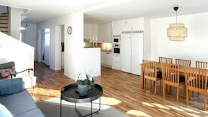 A modern living room with a sofa, a coffee table with a vase, and a dining area with wooden chairs and a table. - 6 Person Holiday Home in Vikbolandet-by Traum (Vikbolandet)