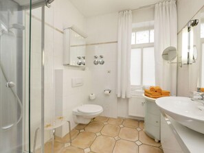 Une salle de bain moderne avec une douche à parois de verre, des toilettes, un lavabo avec un miroir et une fenêtre avec des rideaux.
