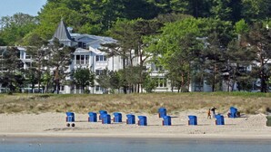 A beachfront property with a large house, beach chairs, and a sandy beach. - Sea Lymphony - in Villa Frigga (Binz)