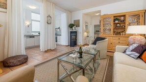 A modern living room with a glass coffee table, a sofa, and a wooden cabinet with glass doors. - Sea Lymphony - in Villa Frigga (Binz)