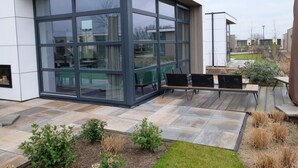 Ein modernes Gebäude mit großen Glasfenstern und einer Terrasse mit Außenbestuhlung.