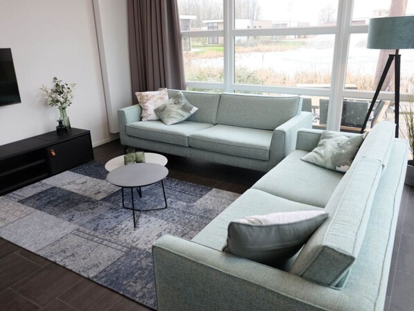 A modern living room with a light green sofa, a small round coffee table, and a black TV stand.