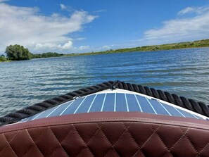 A boat with a brown cushioned seat and a blue-striped deck.