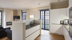 A modern kitchen with white cabinetry, a built-in stove, and a coffee machine. - Thatched Villa With Sauna and Fireplace (Dranske)