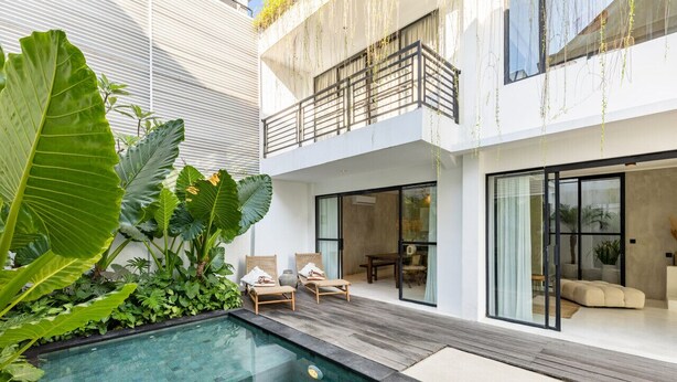 Uma casa moderna com piscina, duas espreguiçadeiras e uma varanda.