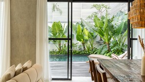 Um interior moderno com uma grande porta de correr de vidro que dá para um jardim exuberante.