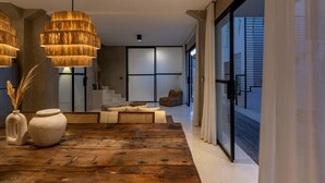 Um interior moderno com uma mesa de jantar de madeira, dois vasos de cerâmica e uma janela ampla com vista para o exterior.