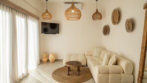Ein modernes Wohnzimmer mit einem beigefarbenen Sofa, einem runden Teppich aus Gewebe und drei hängenden Korbstühlen.