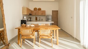 Eine kompakte Küche mit Holzschränken, einer weißen Arbeitsplatte und einem Essbereich mit Holztisch und -stühlen.