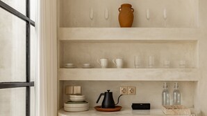 Une cuisine avec un plan de travail blanc, une cafetière noire et divers ustensiles de cuisine.