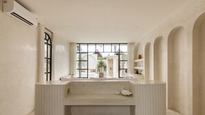 Une salle de bain minimaliste avec une grande fenêtre, un lavabo intégré et un banc.