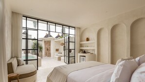 Une chambre spacieuse avec un grand lit, un coin salon et une vue sur l’extérieur.