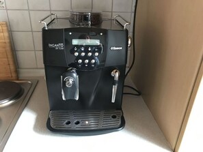 Eine schwarze Kaffeemaschine mit digitaler Anzeige und einer Kaffeemühle auf einer Küchenarbeitsfläche.