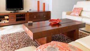 A modern living room with a flat-screen TV, wooden entertainment unit, and a white sofa with a patterned throw. - Belvilla by OYO Casa Roberto (Mijas)