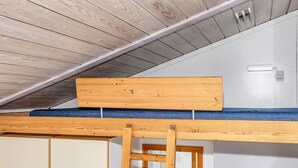 Ein Schlafzimmer im Loft-Stil mit Holzbalkendecke, Etagenbett und einer Leiter.