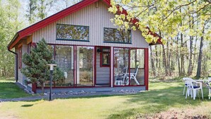 Une cabane avec un toit rouge, de grandes fenêtres et un petit porche.