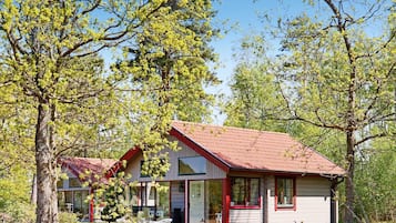A modern house with a red roof, large windows, and a well-maintained lawn.