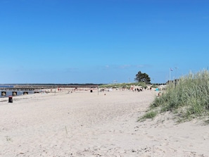 Une plage avec un rivage sablonneux, une jetée et un ciel bleu dégagé.