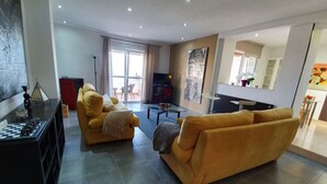 A modern living room with a sofa, a coffee table, and a TV. There is a balcony with a view. - Jose Comfortable Holiday Residence (Rincon de la Victoria)