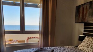 A bedroom with a bed, a window with a view of the sea, and a painting on the wall. - Jose Comfortable Holiday Residence (Rincon de la Victoria)