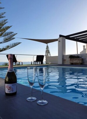 A pool area with a bottle of wine and two glasses on a table, overlooking a scenic view. - Jose Comfortable Holiday Residence (Rincon de la Victoria)