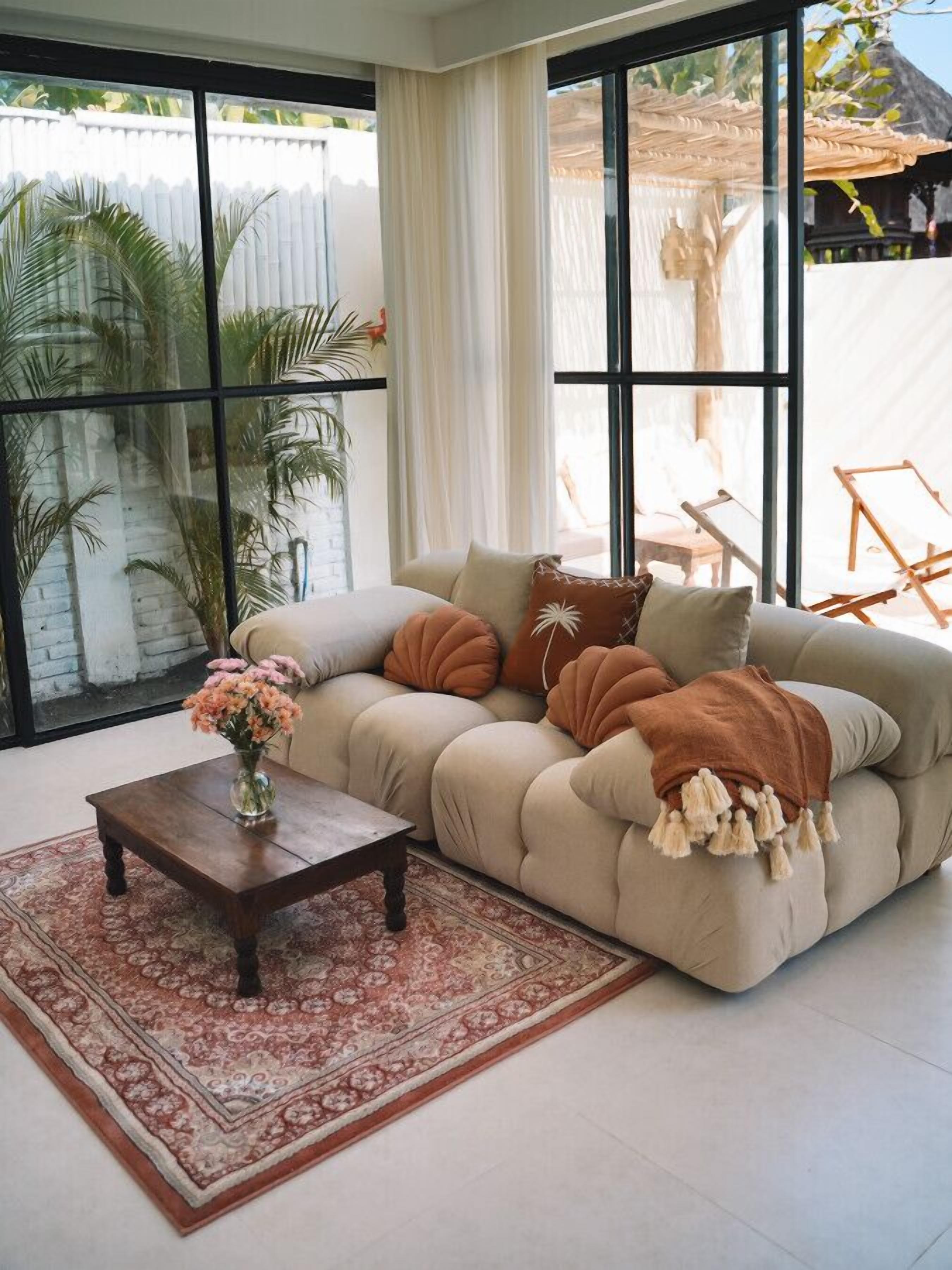 A modern living room with a beige sectional sofa, a wooden coffee table, and a patterned rug.