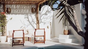 A pool area with two wooden chairs, a white sofa, and a small table.