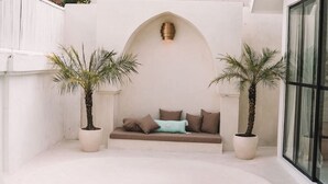 A spa area with a seating area, a hot tub, and two potted palm trees.