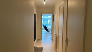 En gang med en stol nær en skydedør, der fører ud til en balkon.