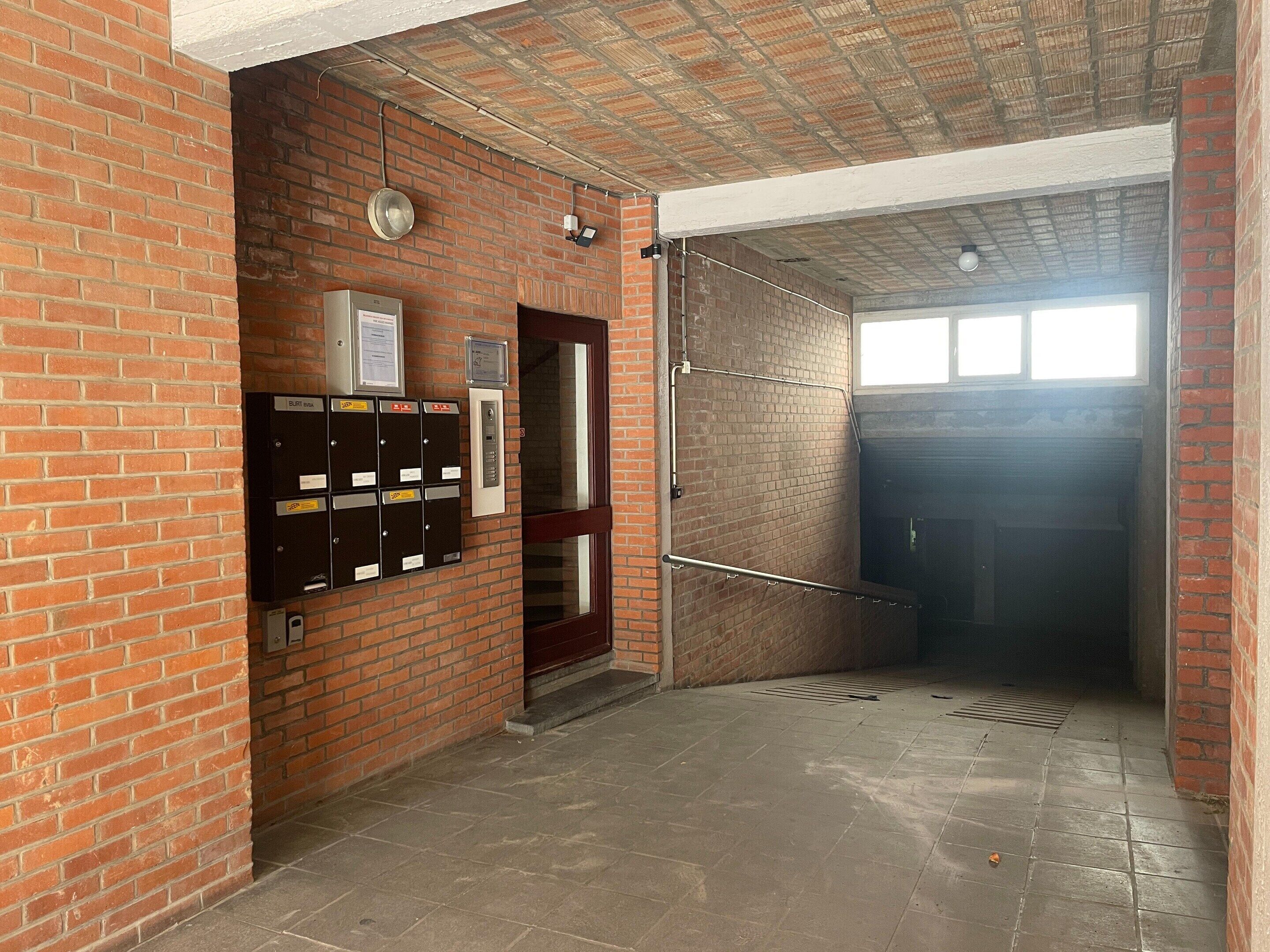 A brick-walled hallway with lockers, a door, and a window.