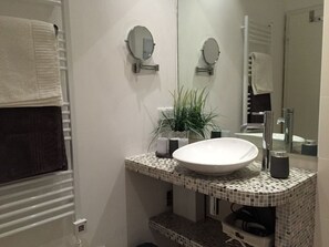 A bathroom with a white sink, two round mirrors, a potted plant, and a towel rack. - Holiday Apartment Seaside (Fehmarn)