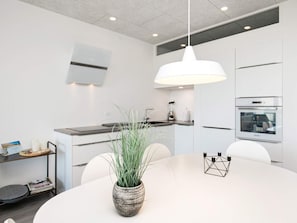 A modern kitchen with white cabinetry, a central island, a built-in oven, and a hanging pendant light. - 4 Person Holiday Home on a Holiday Park in Blokhus (Blokhus)