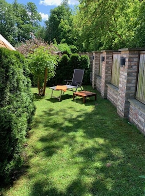 A small, enclosed garden area with a lawn, two chairs, and a table. - Pleasant Apartment in Schwielowsee (Schwielowsee)