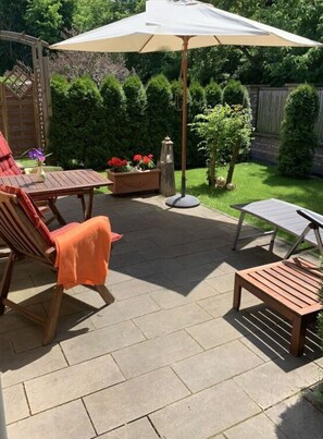 A patio area with a wooden table, chairs, a bench, and a large umbrella. - Pleasant Apartment in Schwielowsee (Schwielowsee)